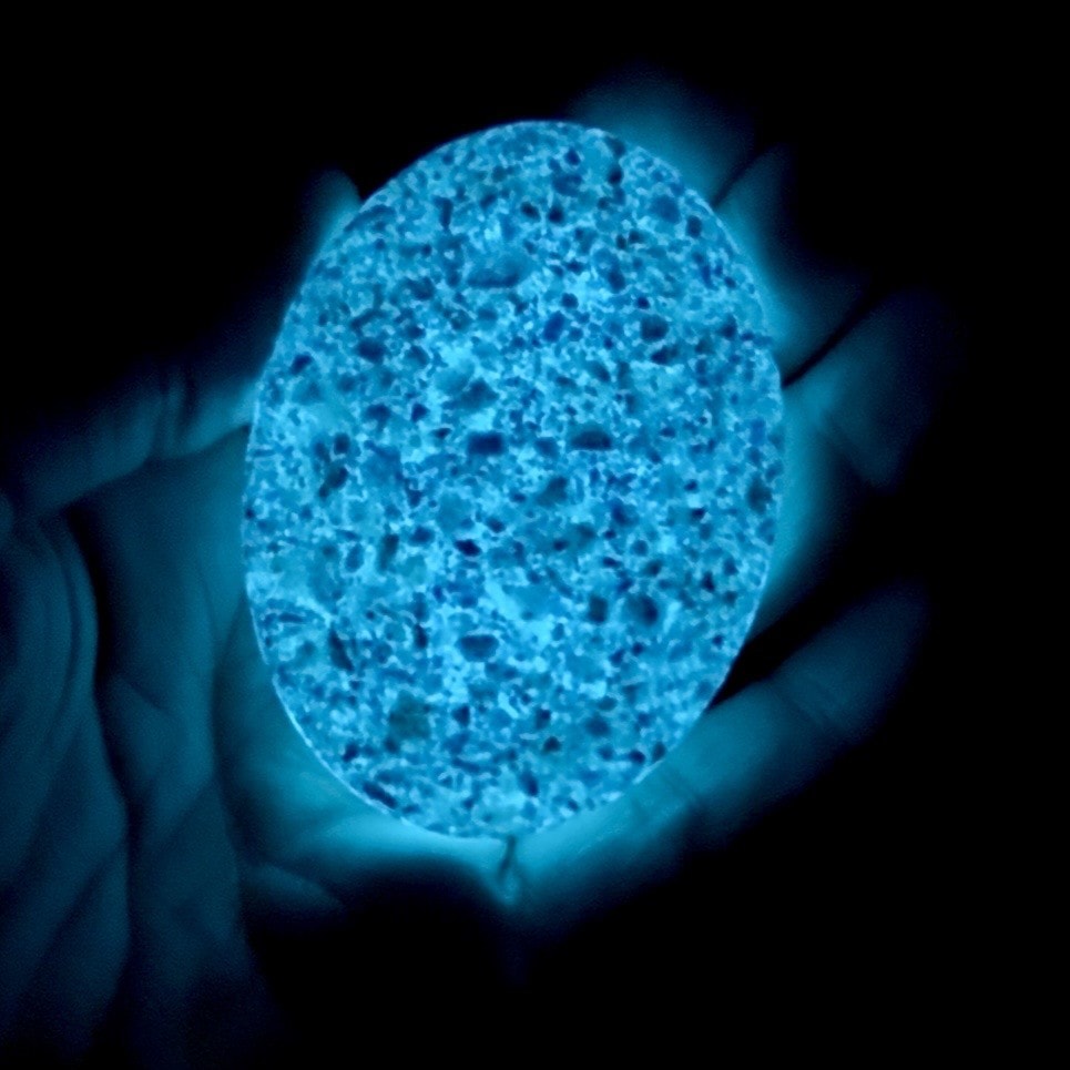 Glowing blue memorial worry stone held in hands